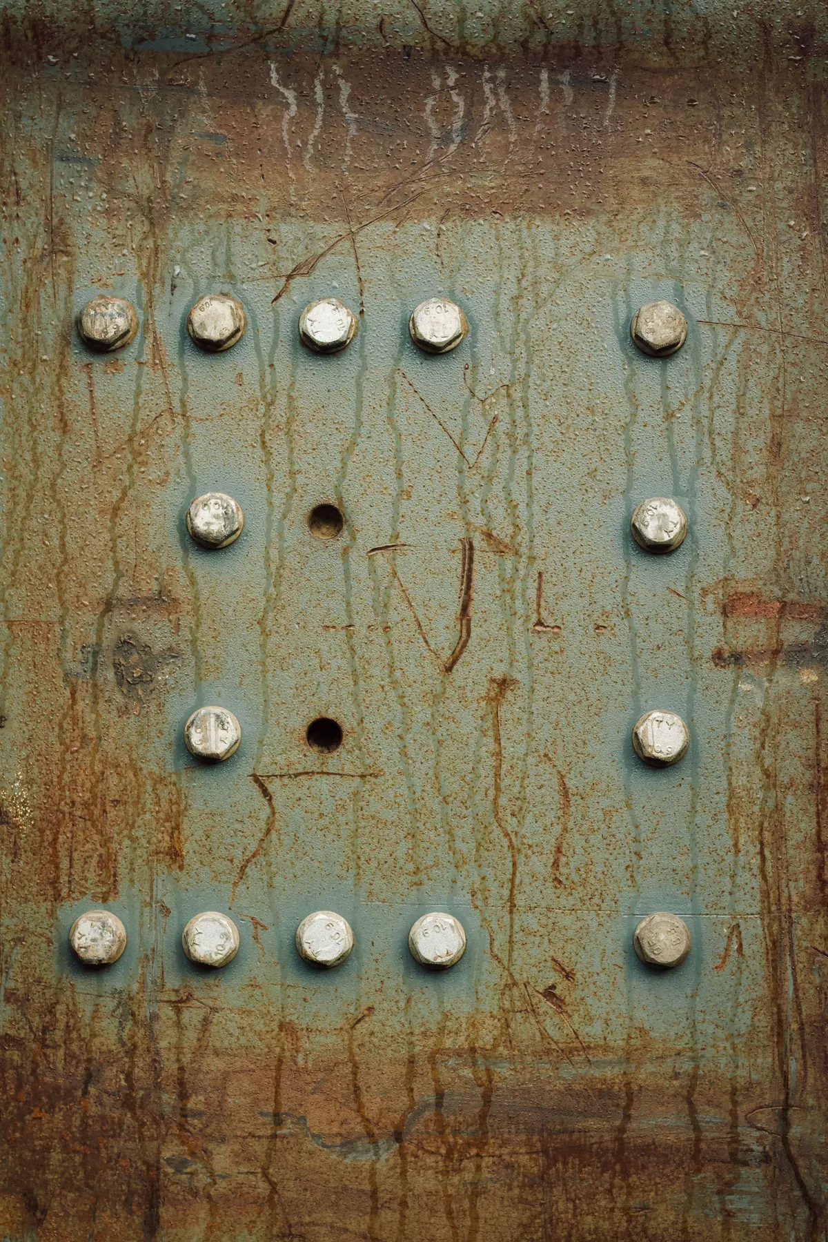 Rivets and traces of weathering on an olive-grey metal surface